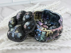 Black and iridescent rhinestone paw print lid viewed from above
